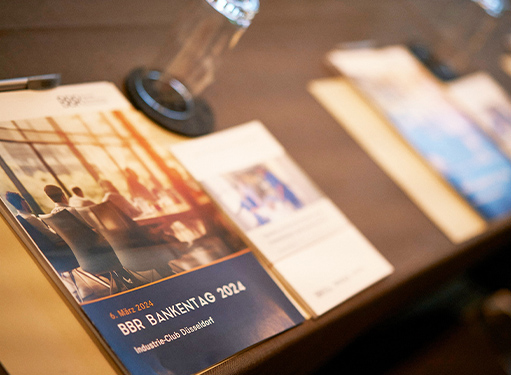 Ein Tisch mit Programmen für den BBR Bankentag 2024 im Industrie-Club Düsseldorf, gut beleuchtet und einladend.
