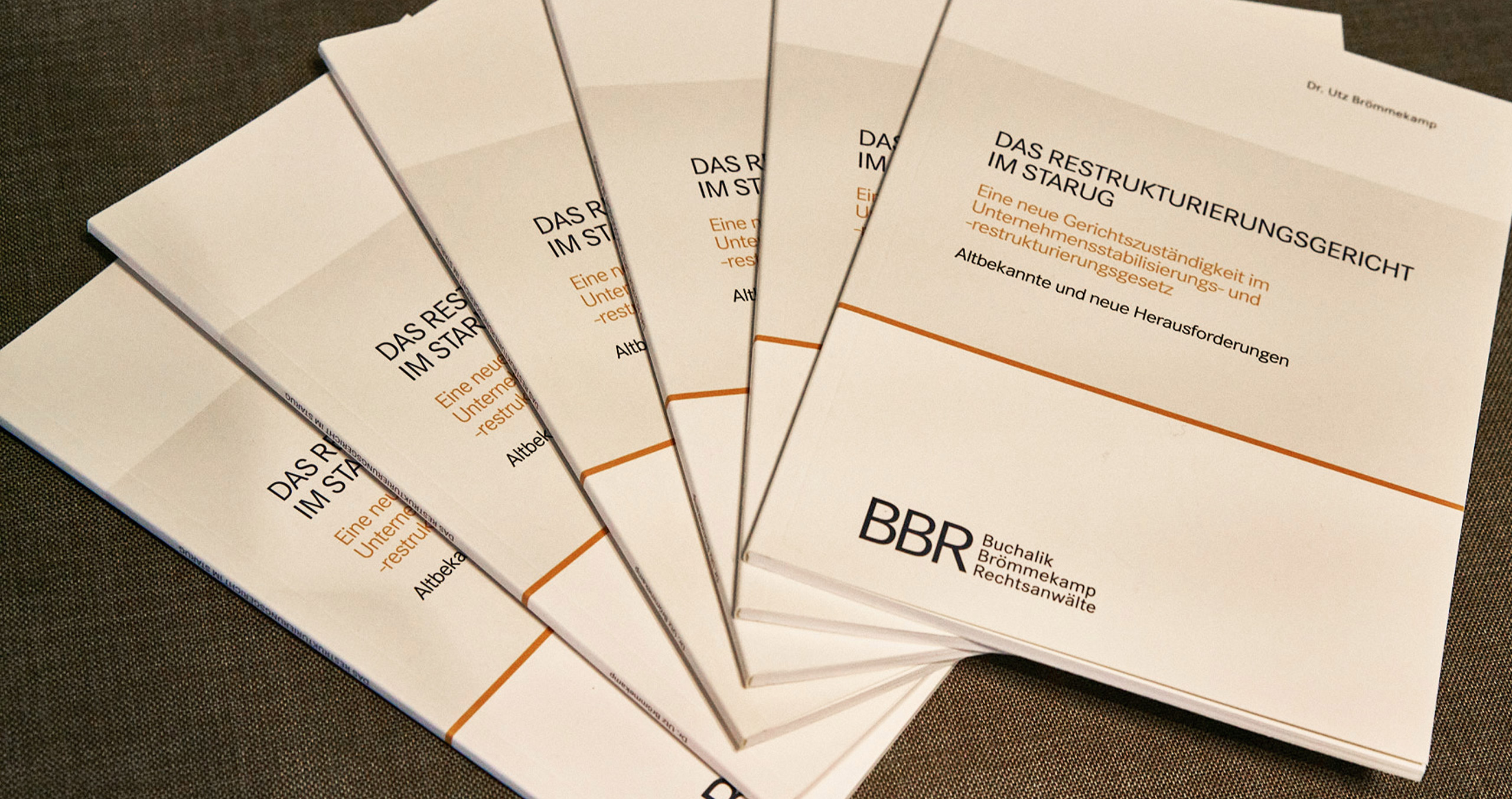 Mehrere Exemplare des Buches über das Restrukturierungsgericht und Unternehmensstabilisierungsgesetz auf einem Tisch.