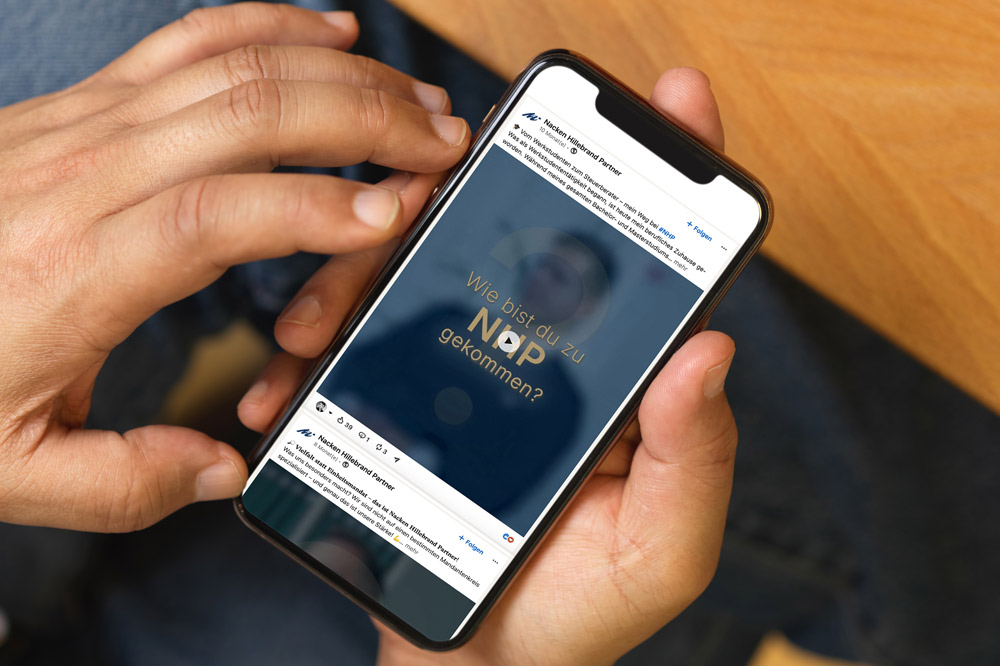 Eine Person hält ein Smartphone, auf dem die Frage 'Wie bist du zu Nap gekommen?' angezeigt wird.