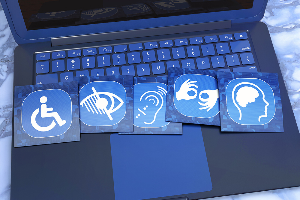 Ein Laptop mit fünf blauen quadratischen Symbolen auf der Tastatur, die Barrierefreiheit für Menschen mit verschiedenen Behinderungen darstellen.