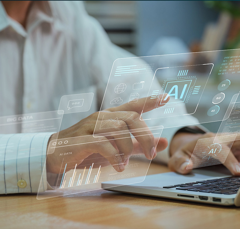 Eine Person interagiert mit einer transparenten, digitalen Benutzeroberfläche, die KI-Daten, Diagramme und technologische Symbole über einem Laptop anzeigt.